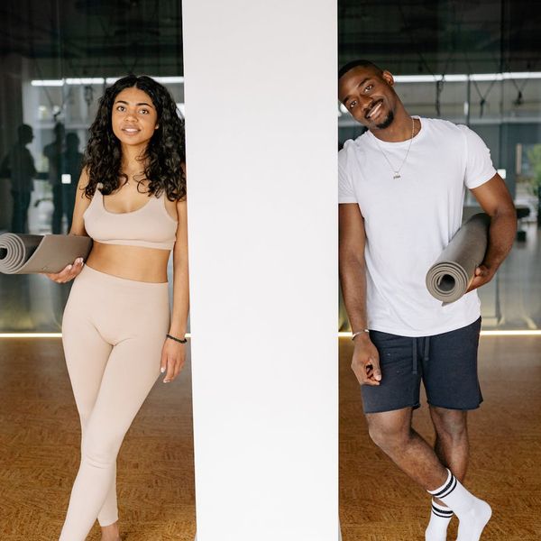 Diverse group of women smiling and holding yoga mats.
